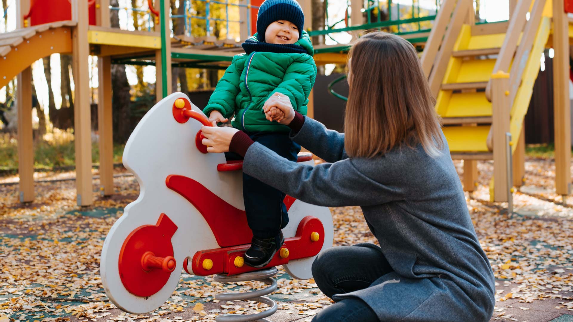 Child playing in a park with an adult nearby